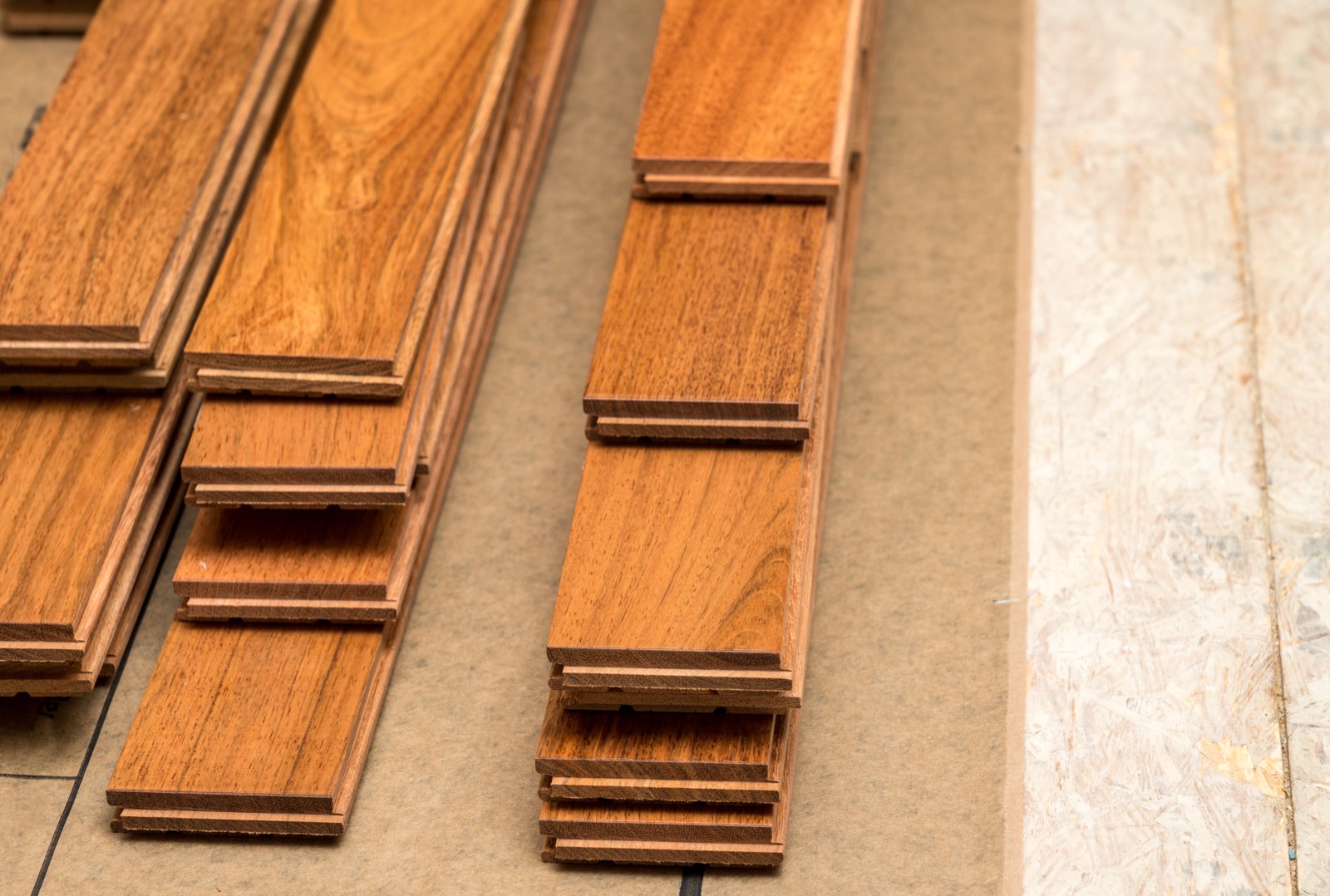 Solid hardwood planks laid out to acclimate on a subfloor before installation
