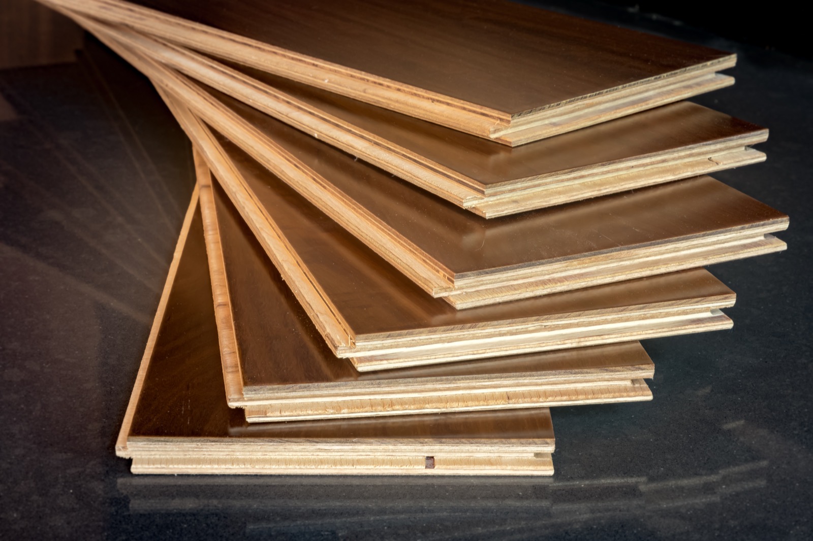 Engineered hardwood planks stacked with plywood core layers visible