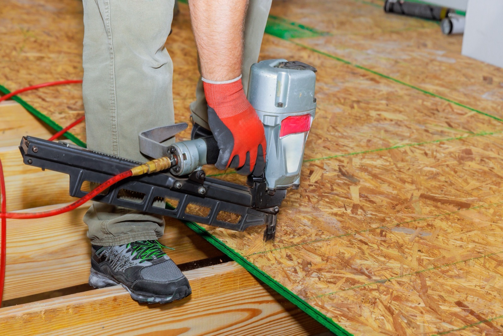 Contractor fastening OSB subfloor panels with a pneumatic nailer