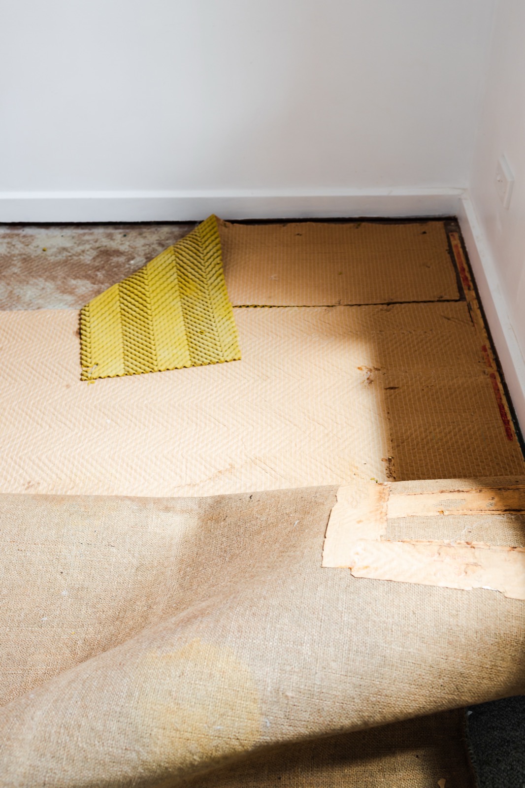Old carpet pulled back to reveal wood flooring underneath
